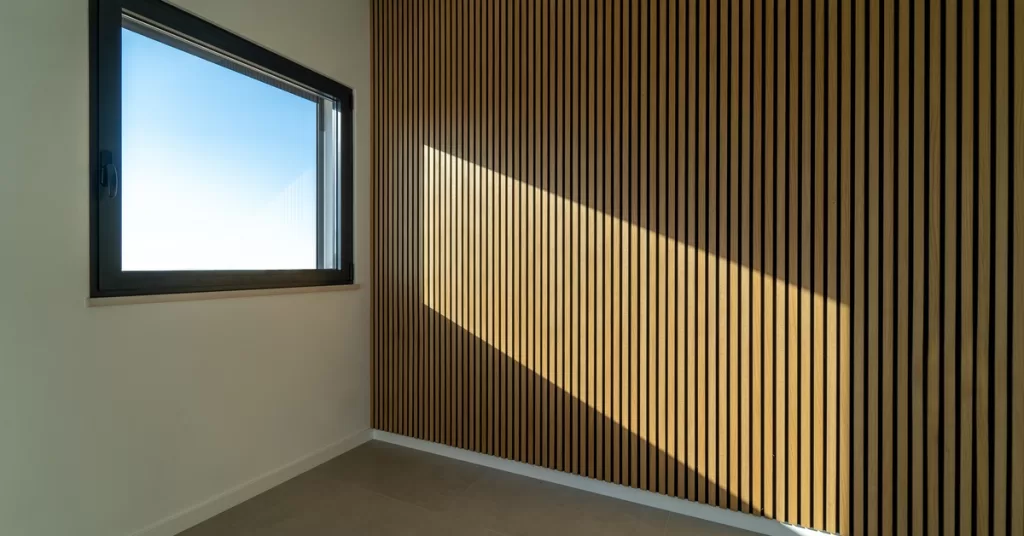 Natural light coming through a window and bouncing off the wooden acoustic paneling installed on an adjacent wall.